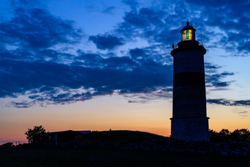 Fototapeta na wymiar Lighthouse shining its light at twilight just after sunset. Location Morups Tange in Falkenberg, Sweden.