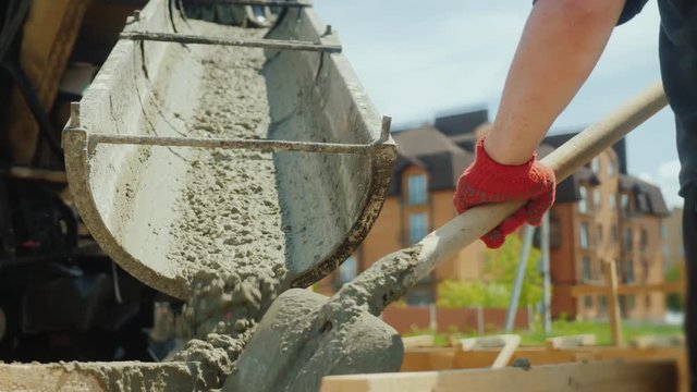 Building a cottage. Workers take concrete from a mixer into a wooden formwork