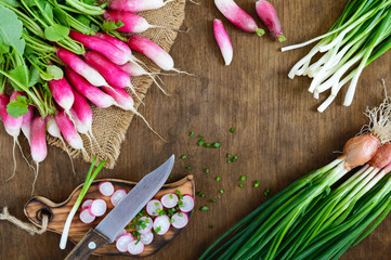 Sliced fresh red radishes and green young onions on white wooden background.  Healthy diet with radish. Ingredients for a light spring vegetable salad. The top view