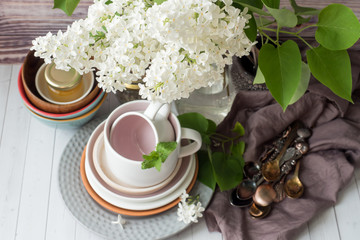 Many different empty tableware. Bouquet of white lilac. Wood background dark napkin