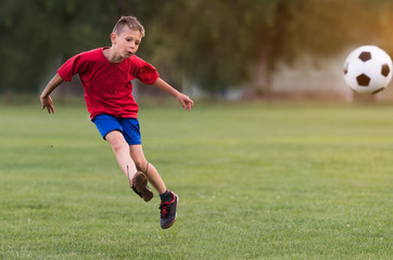 Boy kicking football on the sports field