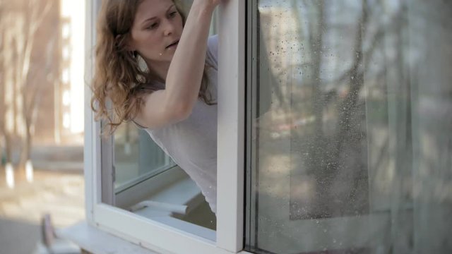 attractive girl washes windows at home. To clean up the house.