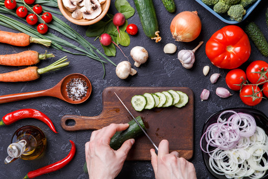 Photo on top of fresh vegetables, mushrooms, cutting board, oil, knife, hands of cook