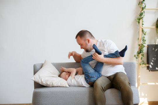 Image of young father with son playing on sofa
