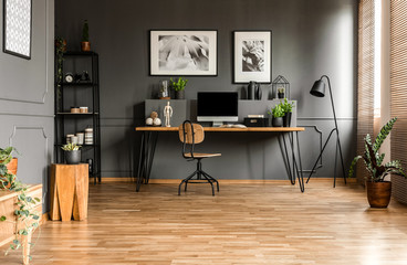 Real photo of spacious start-up office interior with a single chair at a wooden desk with computer...
