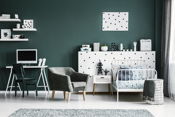 Workspace with a computer in a stylish bedroom interior for a teenage student with white furniture and dark green walls