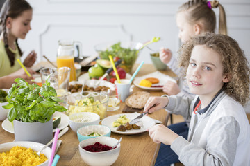 Boy eating healthy dinner during party with friends at home