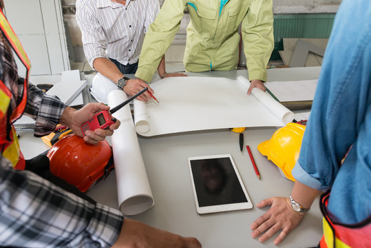 A group of male and female engineers talking blueprint at meeting. to plans for the construction of the building. analyzing brainstorming, teamwork, meeting concept..