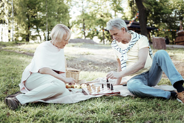 Mental activities. Attentive man playing chess with his woman and bowing head while looking downwards