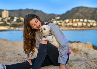 Girl playing with maltichon dog in the beach
