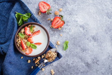 Top view of Organic Healthy Breakfast Food. Granola with greek yogurt and strawberry on gray concrete table background. Copy space