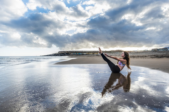 pilates  body  stay position for young caucasian woman on the shore at the beach. scenic image for body health concept. yoga balanced in contact and feeling with the nature. meditation leisure time.