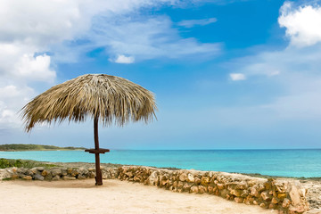Fototapeta na wymiar Palm leaf beach umbrella on a deserted shore