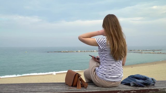 Barcelona, Spain. Girl sits on the bench on the Barceloneta beach and looking at the sea