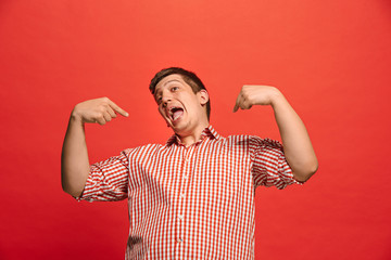 The happy business man standing and smiling against red background.