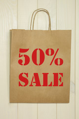 50 sale. Paper shopping bag on a wooden background