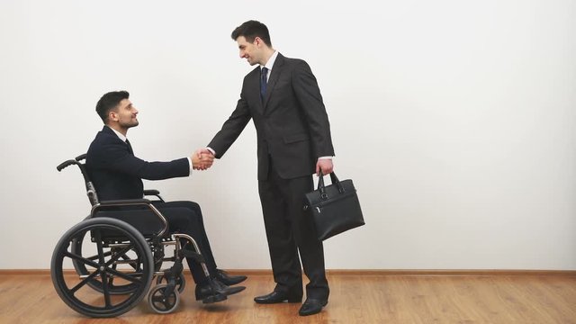 The disabled and a businessman handshake on the white wall background