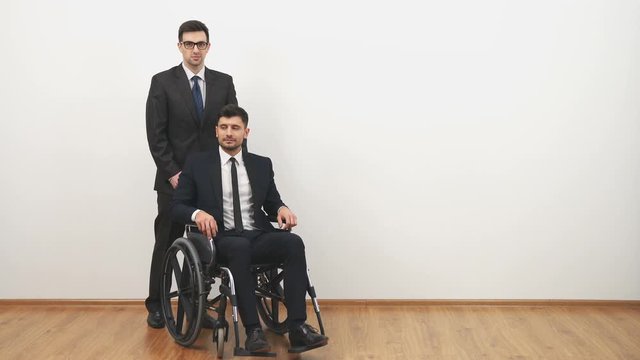 The businessman walking with a disabled on a wheelchair on the white background