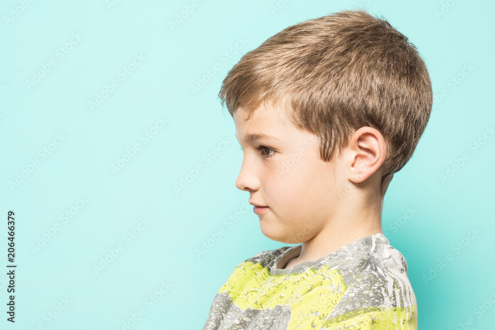 Wall mural Serious child in profile on a blue background