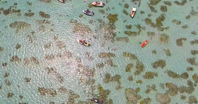 Aerial view of boats and people swimming in turquoise sea of Rio do Fogo, Brazil