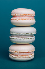 Orange ang green pastel macarons isolated on the blue background. Close up, front view