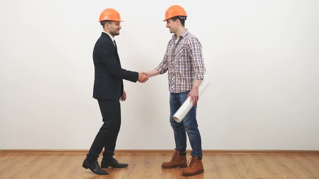 The man and an engineer with a drawing discuss on the white background