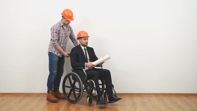 The businessman on the wheelchair and a engineer dicuss with a drawing