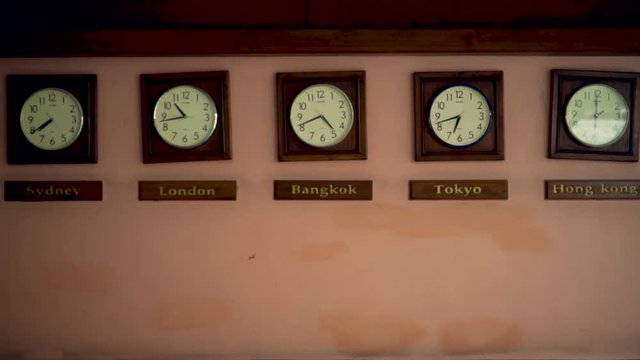 Timezone old  clocks showing different time hanging on dirty orange wall