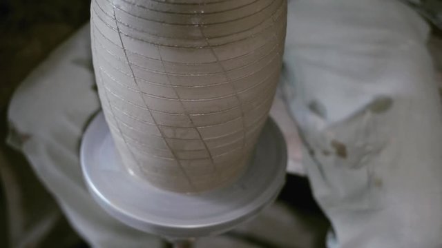 Closeup potter warm up glazes along all clay jar by hair dryer on potter's wheel