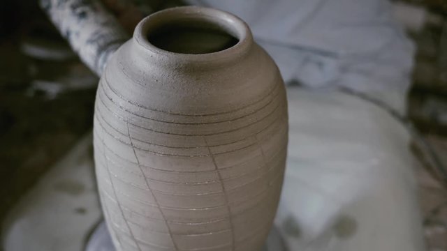 Closeup potter warm up glazes along the clay jar by hair dryer on potter's wheel