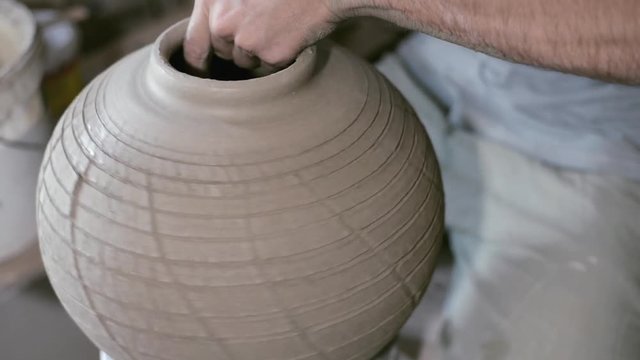 Closeup potter rotate jar with crack texture on potter's wheel and make wide neck
