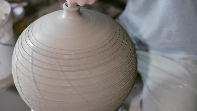 Closeup potter rotate jar with crack texture on potter's wheel and make narrow neck