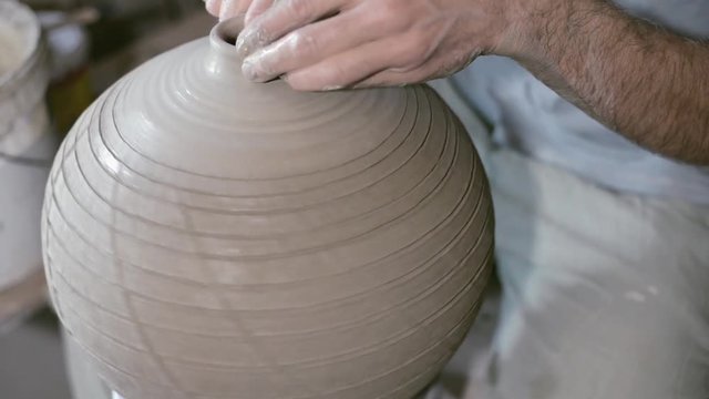 Closeup potter rotate jar with crack texture on potter's wheel and make neck