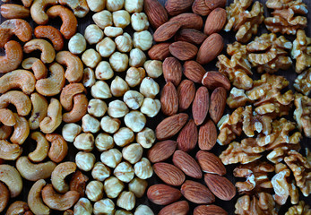 Nuts background, walnut, almond, hazelnut and cashew nuts in order on wooden table