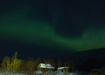 Wooden house on the background of the aurora in winter