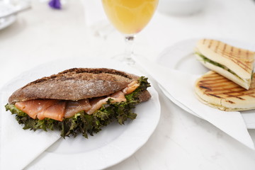 Bread with salmon fish and fresh orange juice in a glass for breakfast on a white table