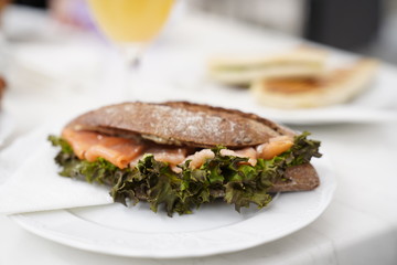 Bread with salmon fish and fresh orange juice in a glass for breakfast on a white table