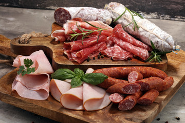 Food tray with delicious salami, ham,  fresh sausages and herbs. Meat platter with selection