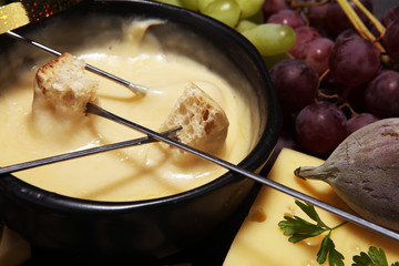 Gourmet Swiss fondue dinner on a winter evening with assorted cheeses on a board alongside a heated pot of cheese fondue