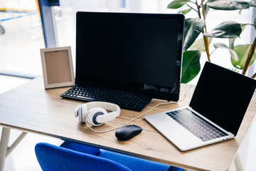 closeup view of workplace with laptop, headphones, photo frame and computer at table