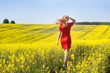 Young woman cheering in the rape seed field