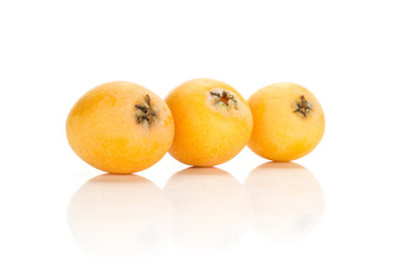 Three fresh orange Japanese loquats in row isolated on white background.