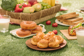 Healthy picnic for a summer vacation with freshly baked croissants, fresh fruit and fruit salad, sandwiches and a glass of refreshing orange juice laid out on a red and white checked cloth and hamper