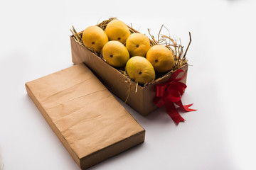 Alphonso mangoes in a gift box over grass and tied with red ribbon, selective focus