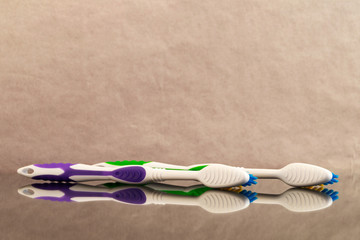 Brushes for cleaning teeth from plastic, laid parallel to the side with reflection in the glass.