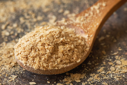 Closeup of nutritional brewers yeast flakes in wooden spoon