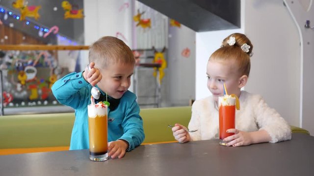 Milkshake cocktail - children in cafe, cute little girl and boy eating cream with spoon