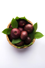 Fresh Kokum or Garcinia indica fruit from India isolated over white or in cane basket with leaves....