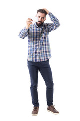 Confident macho stylish bearded man touching hair looking at mobile phone reflection. Full body isolated on white background. 