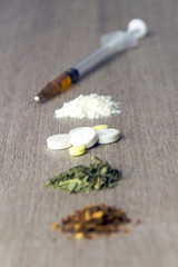 the road to death: in a row are narcotic substances in the degree of increased exposure and danger, tobacco, weed, amphetamine, cocaine and heroin, front top, short focus on tablets